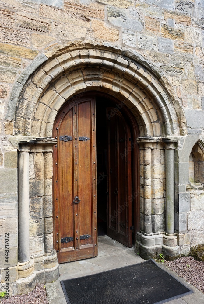 Medieval stone arch with heavy wooden door half open in Europe