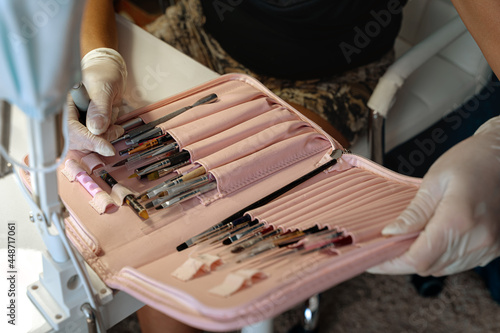 A set of manicure brushes in a case is held in the hands of a nail master. Close-up, selective focus..