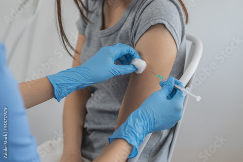 Covid-19 coronavirus hand of young woman nurse doctor giving syringe vaccine  inject shot to asian arm s patient. Vaccination  immunization or disease prevention against flu or virus pandemic concept.