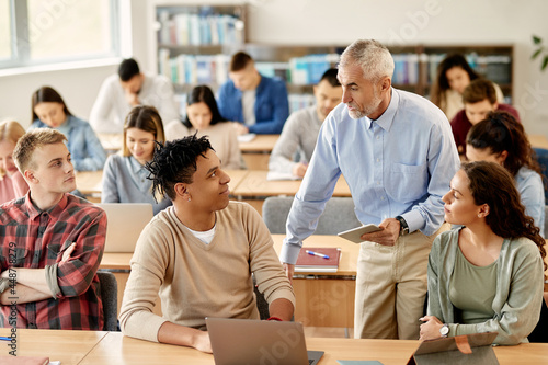 Senior teacher talking to his students at university classroom.