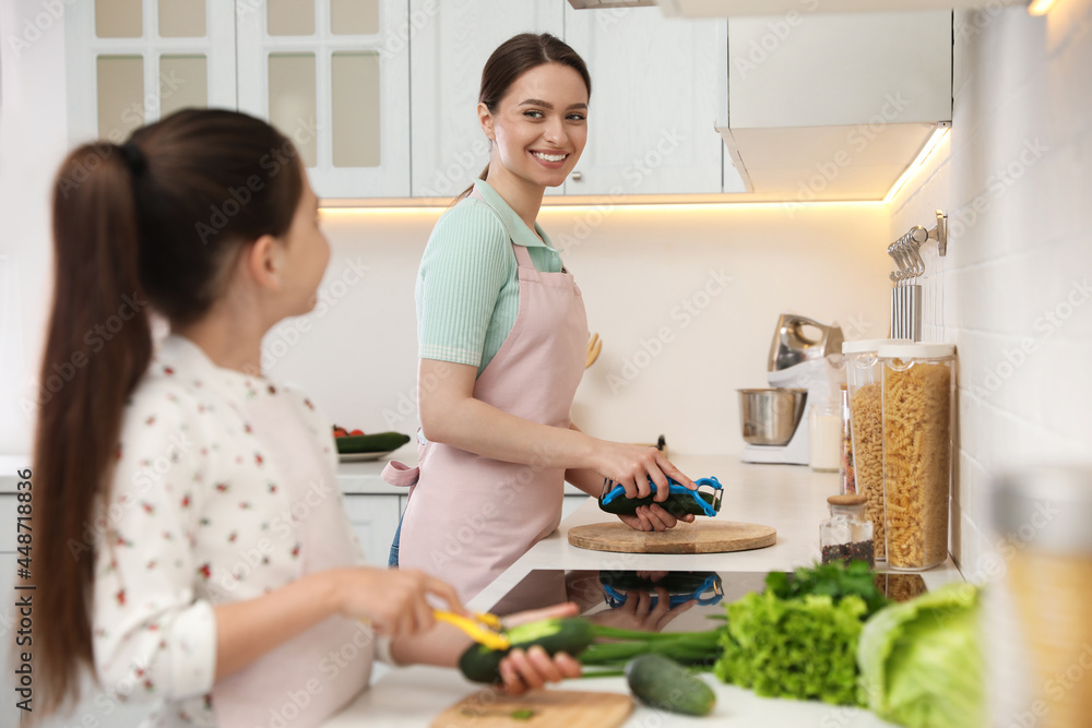 Mother and daughter peeling vegetables at kitchen counter