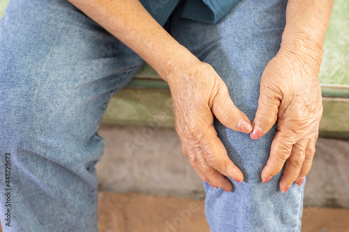 Close up shot of sitting seniors knees with hands touching or grabbing due to feeling pain and hurt shows elderly disease due to muscle weakness and joint ache which is health care problem. © Wonchalerm