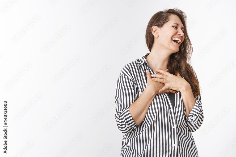 Happy and touched middle-aged european mother laughing and holding hands grateful on chest looking right pleased and delighted, thankful for cute gift for women day, chuckling amused over white wall Happy and touched middle-aged european mother laughing and holding hands grateful on chest looking right pleased and delighted, thankful for cute gift for women day, chuckling amused over white wall