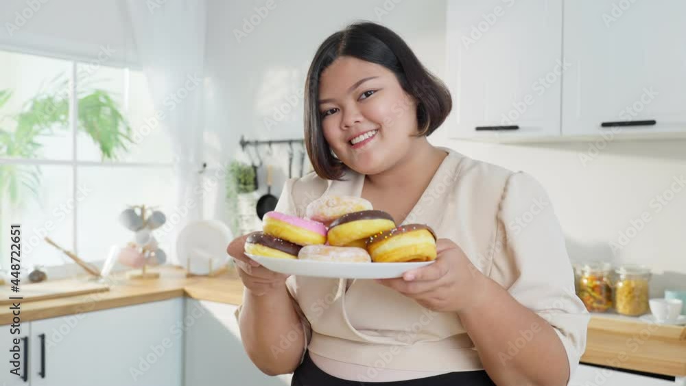 Portrait of Asian oversize big women holding donut on plate in kitchen. Portrait of Asian oversize big women holding donut on plate in kitchen.
