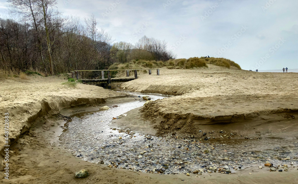 Top view of a beach washed by sea water, with rocks. Wet sand is drawings rivers and stones. High quality photo