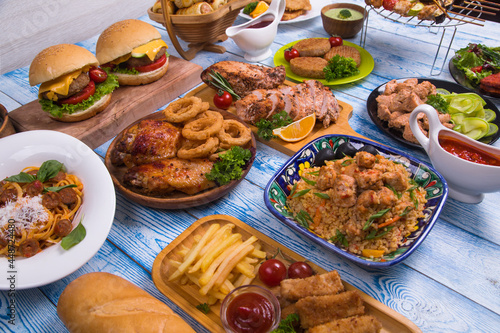 Wooden table full of delicious grilled bbq and fried food. Meat and vegetables. Summer picnic background. Delicious dinner.