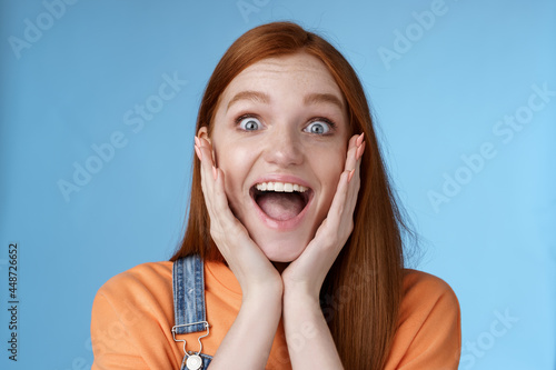 Impressed excited overwhelmed young redhead girlfriend fan screaming thrilled express afection adore awesome music band yelling happily reacting surprised astonished, standing blue background photo