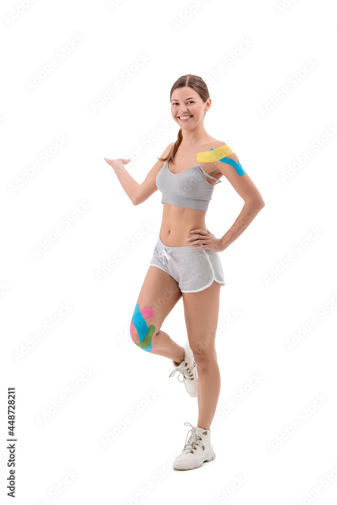 Woman showing kinesio tapes taped to her body. Full-length portrait of woman with Bright medical kinesio tapes Woman showing kinesio tapes taped to her body. Full-length portrait of woman with Bright medical kinesio tapes