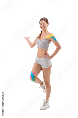 Woman showing kinesio tapes taped to her body. Full-length portrait of woman with Bright medical kinesio tapes