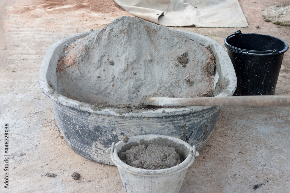 Cement and hoe in plastic bucket for mixer in construction site. Cement and hoe in plastic bucket for mixer in construction site.