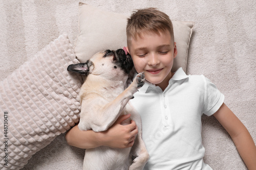 Boy with his cute pug lying on floor at home  top view