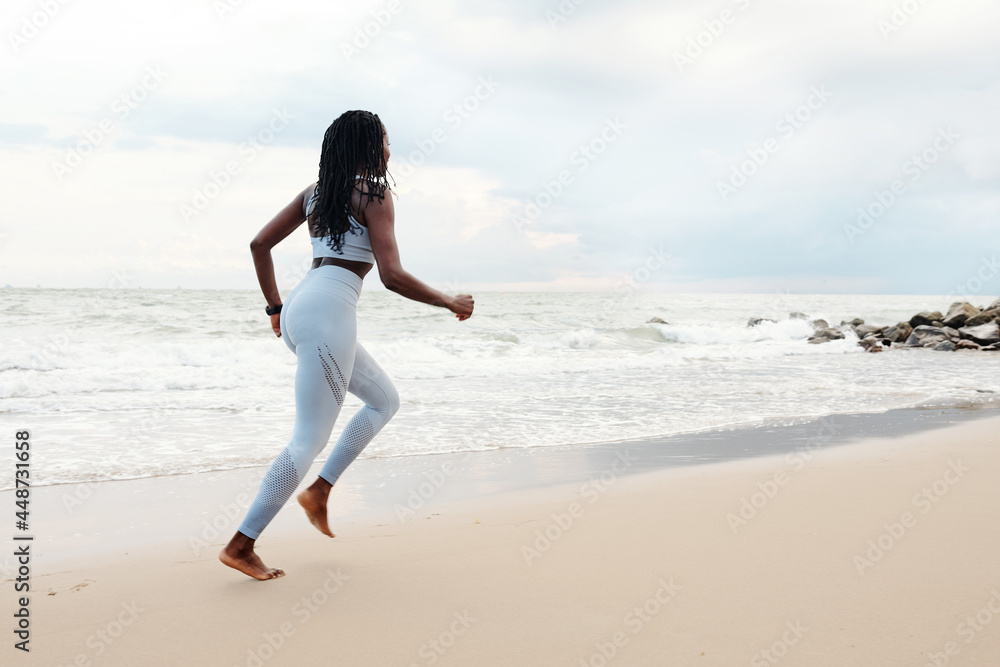 Young woman enjoying running on beach in the morning on summer day Young woman enjoying running on beach in the morning on summer day