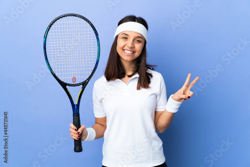 Young woman tennis player over isolated background showing victory sign with both hands