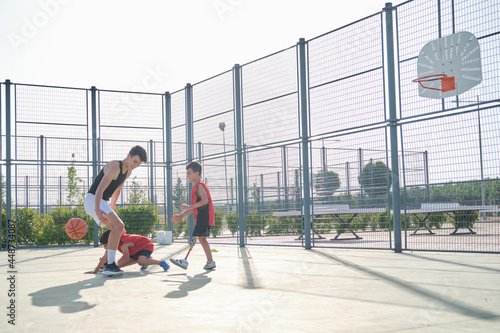 Three brothers playing basketball, one of them has a leg prosthesis.