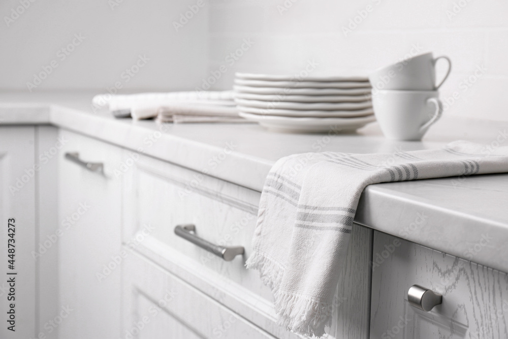 Soft kitchen towel and dishware on countertop indoors, space for text Soft kitchen towel and dishware on countertop indoors, space for text
