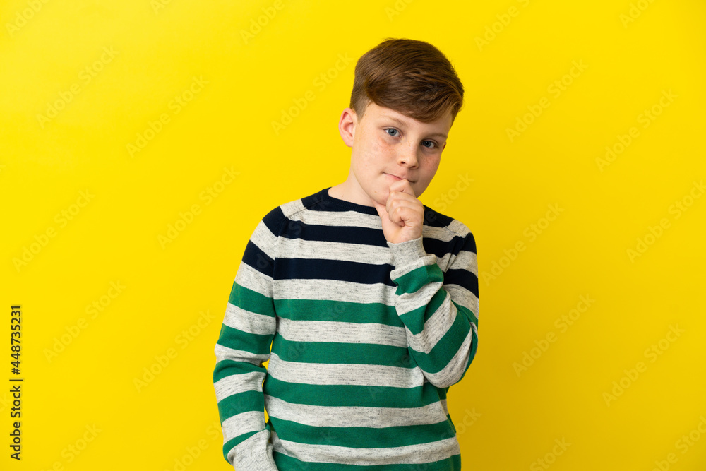 Little redhead boy isolated on yellow background having doubts and thinking Little redhead boy isolated on yellow background having doubts and thinking