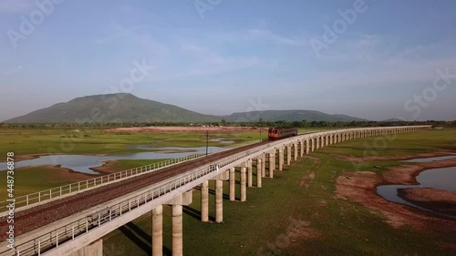 Wallpaper Mural Aerial view of Thailand diesel train runs on railway bridge over green grass in the lake area of Pa Sak Jolasid dam with blue sky and mountains are background in Lopburi province. Torontodigital.ca