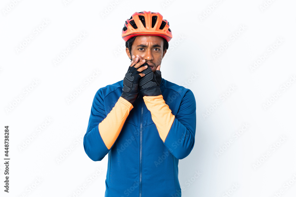 Young cyclist man with braids over isolated background covering mouth with hands Young cyclist man with braids over isolated background covering mouth with hands