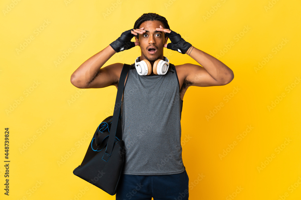 Young sport African American man with braids with bag isolated on yellow background with surprise expression Young sport African American man with braids with bag isolated on yellow background with surprise expression