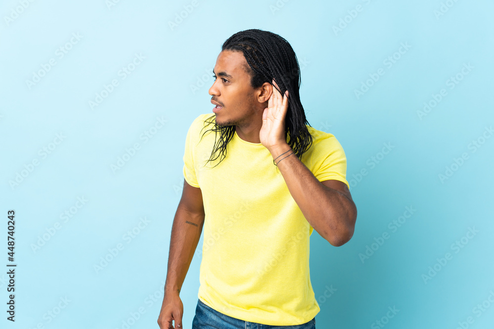 Delivery African American man with braids isolated on white background listening to something by putting hand on the ear Delivery African American man with braids isolated on white background listening to something by putting hand on the ear