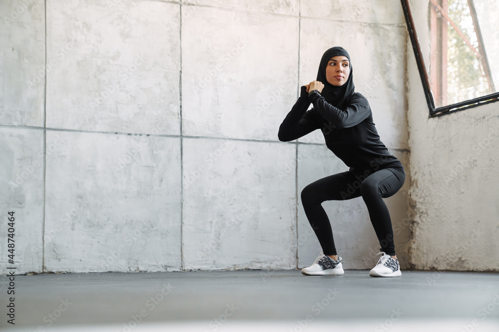 Young muslim woman in hijab doing exercise while working out indoors Young muslim woman in hijab doing exercise while working out indoors