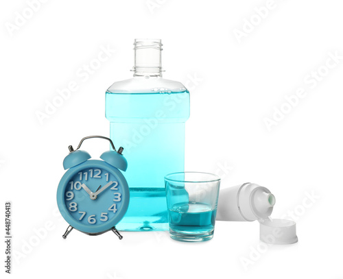 Mouthwash, paste and alarm clock on white background