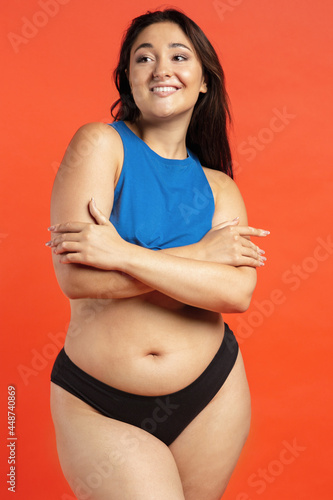 Young beautiful plump woman in cotton underwear on orange background