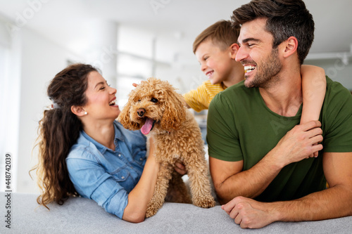 Happy family playing, having fun with dog at home