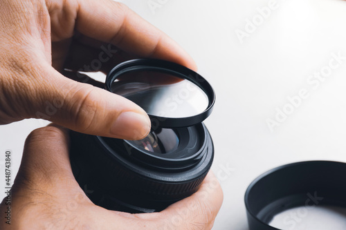 Human hand is installing UV filter to camera lens photo