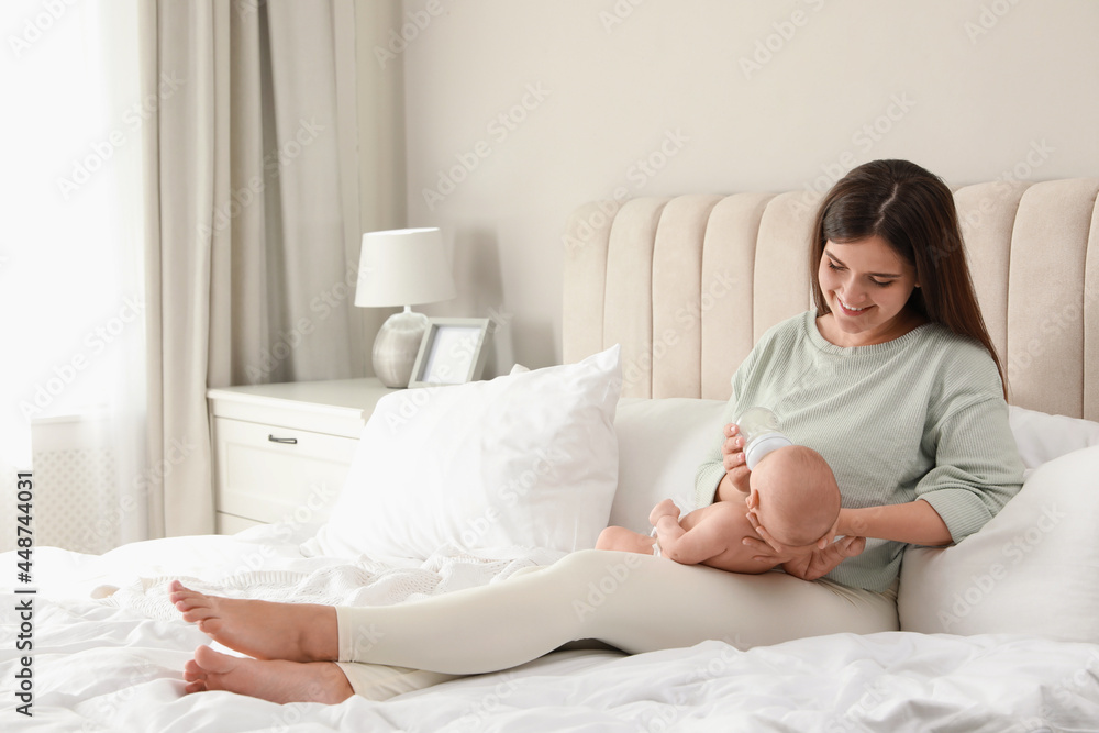 Young woman breastfeeding her little baby on bed at home Young woman breastfeeding her little baby on bed at home