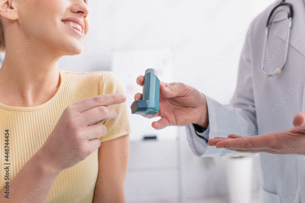 cropped view of asthmatic woman smiling near doctor pointing at inhaler - obrazy, fototapety, plakaty 