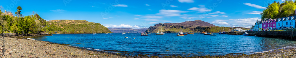 An ultra-wide view of the beach, bay in the town of Portree on the Isle of Skye, Scotland on a summers day