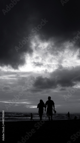 Couple Walking at Beach While Cloudy Dark Sunset Monochrome