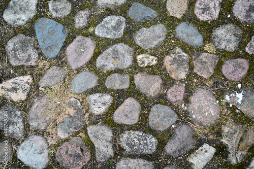 Paving stone, texture background. Cobble pattern. Old road detail. Ancient path. Rock way. Abstract wallpaper. Natural building material. DIY pavement at the backyard. Red, blue, gray tints. Close-up