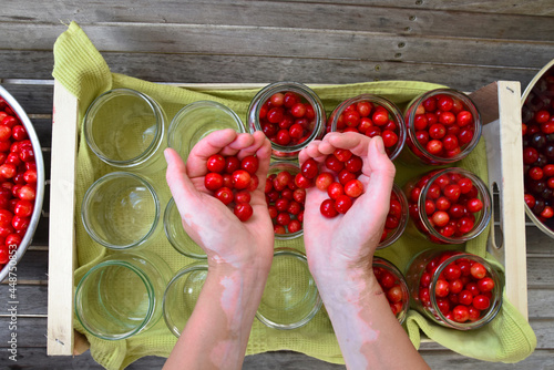 Cherry compote being prepared for winter preservation in a big pot on a stove, where all bacteria is destroyed because of heat.