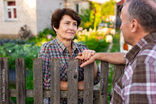 neighbors man and woman chatting near the fence in the village photo