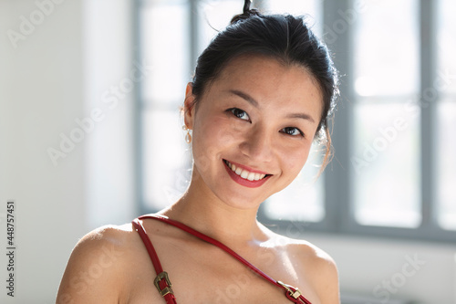 Young Asian girl in a traditional Chinese dress with gathered hair looks at the camera and smiles