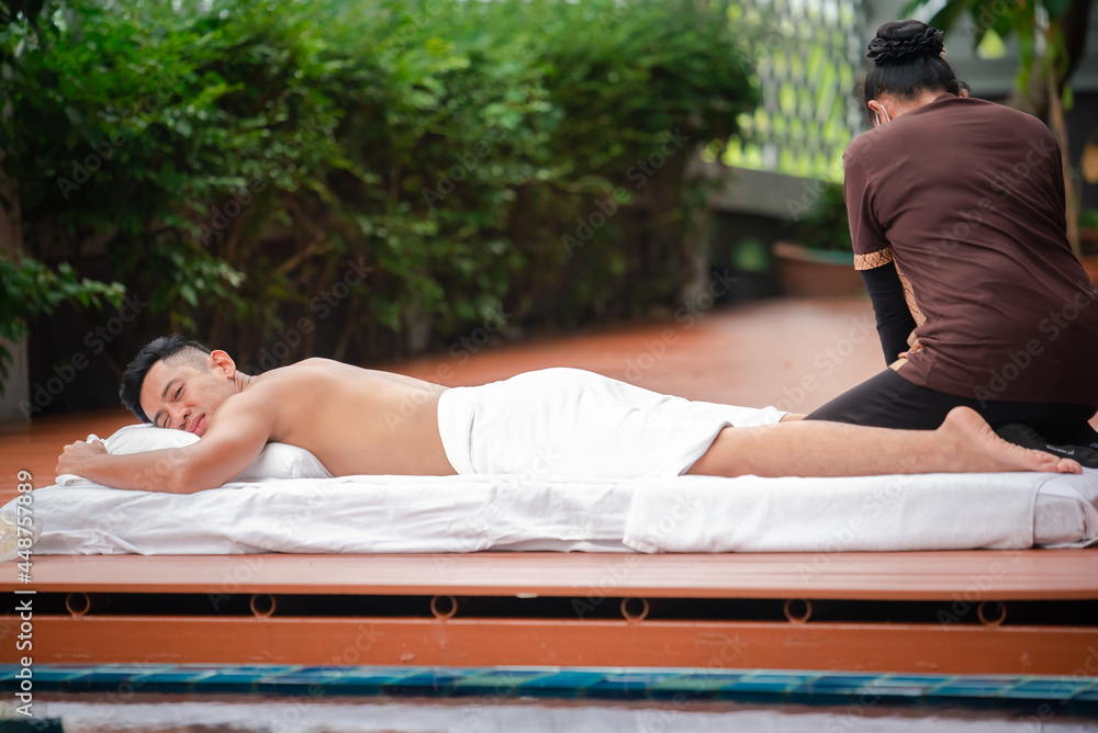 Asian man enjoy a massage by the resort's pool.