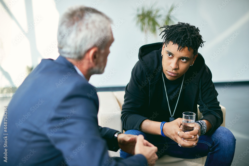 Obraz premium African American adolescent during psychotherapy with mental health professional at counselling center.