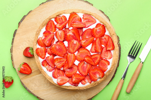 Wooden board with tasty strawberry pie on color background