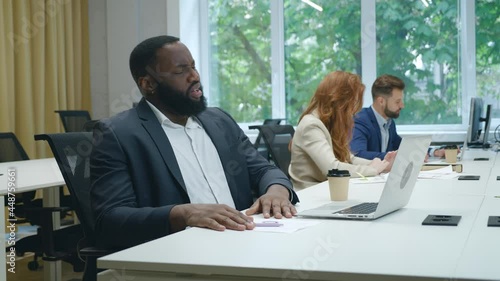 Wallpaper Mural Depressed african man office worker feeling bored while working at laptop in office. Sad bsinessman tired of office work Torontodigital.ca