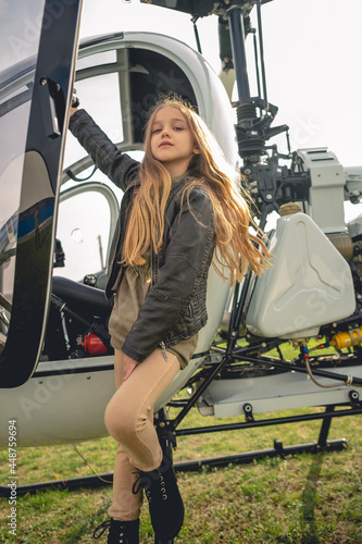 Confident preteen girl standing on footboard of open helicopter photo