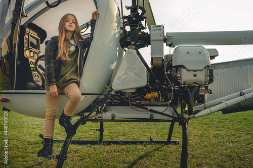 Tween girl posing near open cockpit of helicopter photo