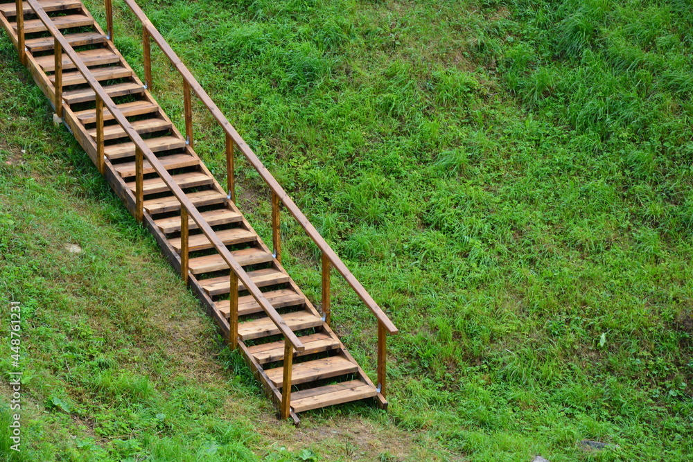 A wooden staircase goes up the hill. Climbing a high hill using the stairs.