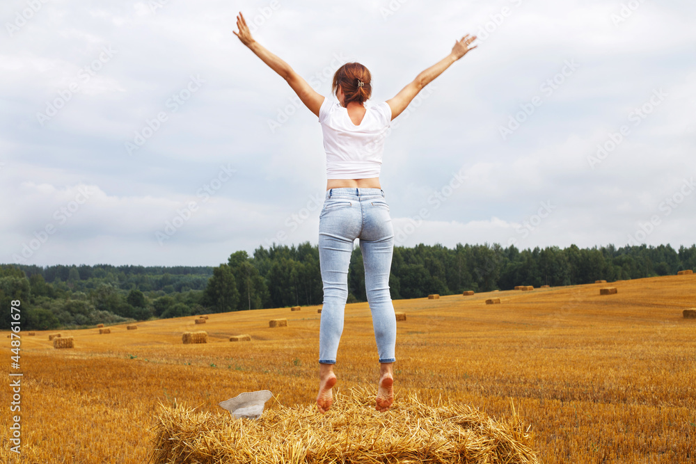 girl with straw hat stands on a haystack on a bale in the agricultural field after harvesting girl with straw hat stands on a haystack on a bale in the agricultural field after harvesting