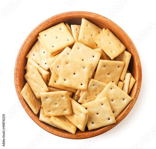 Crackers in a wooden plate on a white background, isolated. The view from top