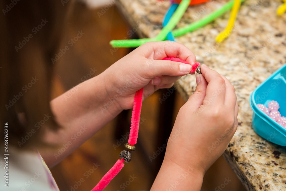 Female child stringing beads onto pipe cleaner