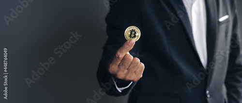 Handsome Investor Businessman in black suit holding a golden bitcoin on dark background, trading, Cryptocurrency, Digital virtual currency, alternative finance and investment Concept..
