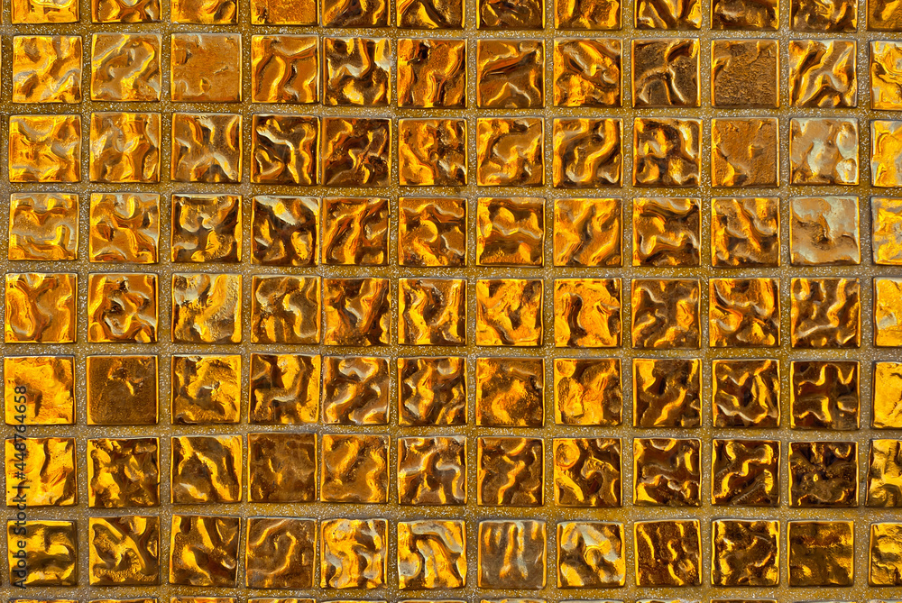 Texture of a wall made of small stones. The wall is clad with yellow granite cubes.