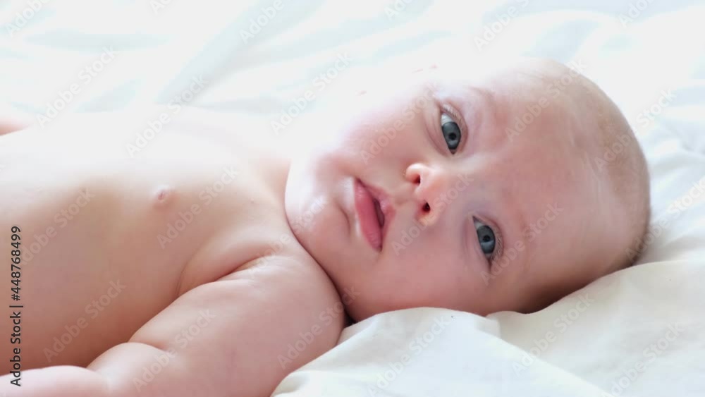 Portrait of Newborn. Beautiful Baby Face Close up. Small Child smiles and laughs. Cute little Baby is looking into the Camera. Newborn Health. Infancy, Childhood, and Health Concept. 4K Portrait of Newborn. Beautiful Baby Face Close up. Small Child smiles and laughs. Cute little Baby is looking into the Camera. Newborn Health. Infancy, Childhood, and Health Concept. 4K